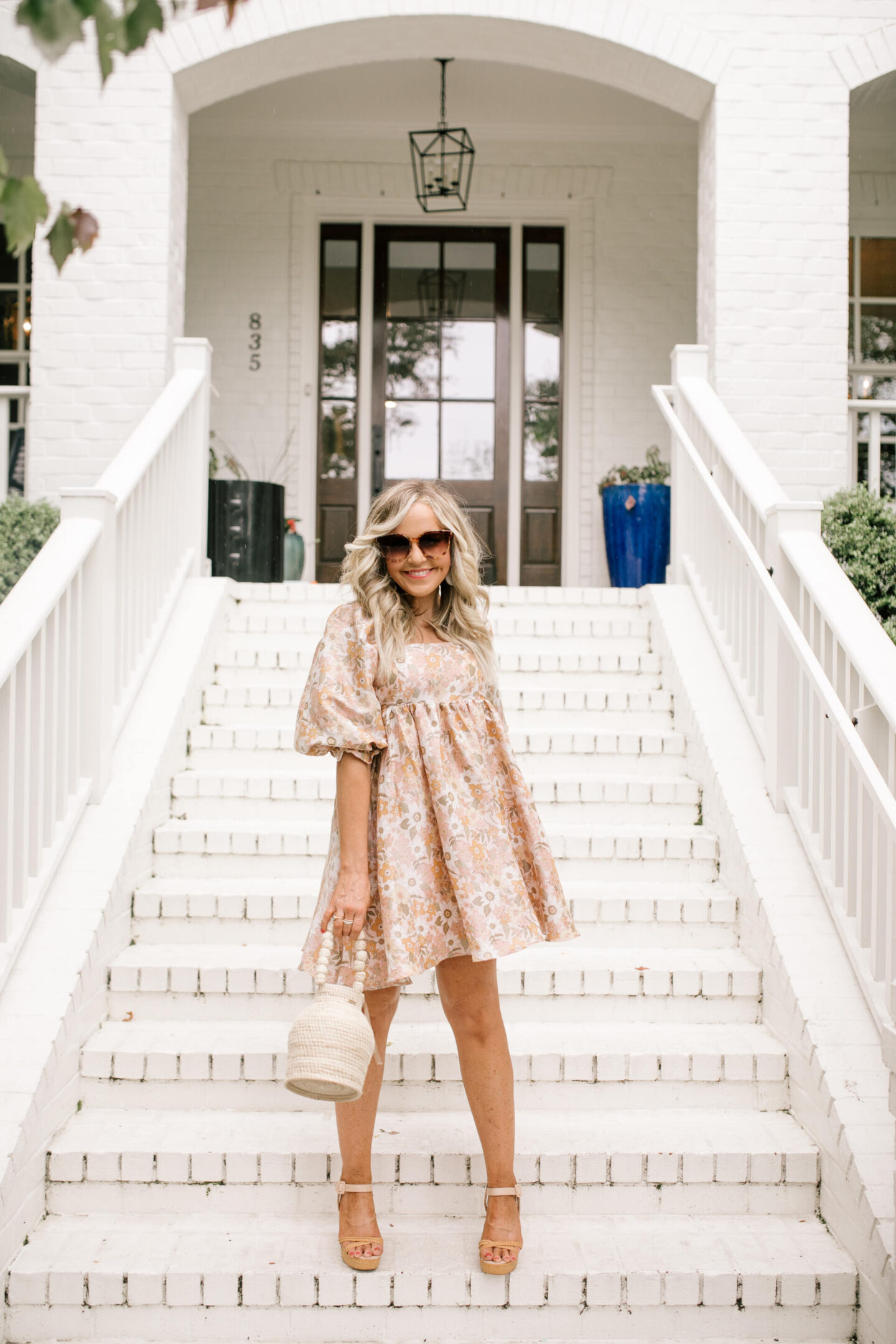 Summer Dress by popular Nashville fashion blog, Hello Happiness: image of a woman standing on some white brick stairs and wearing an In Bloom dress platform sandals and holding a bucket tote. 