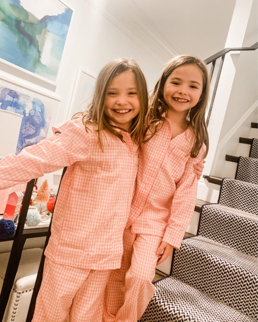 Valentine's Day Gifts by popular Nashville life and style blog, Hello Happiness: image of two girls standing on a stair case and wearing matching pink plaid pajamas. 
