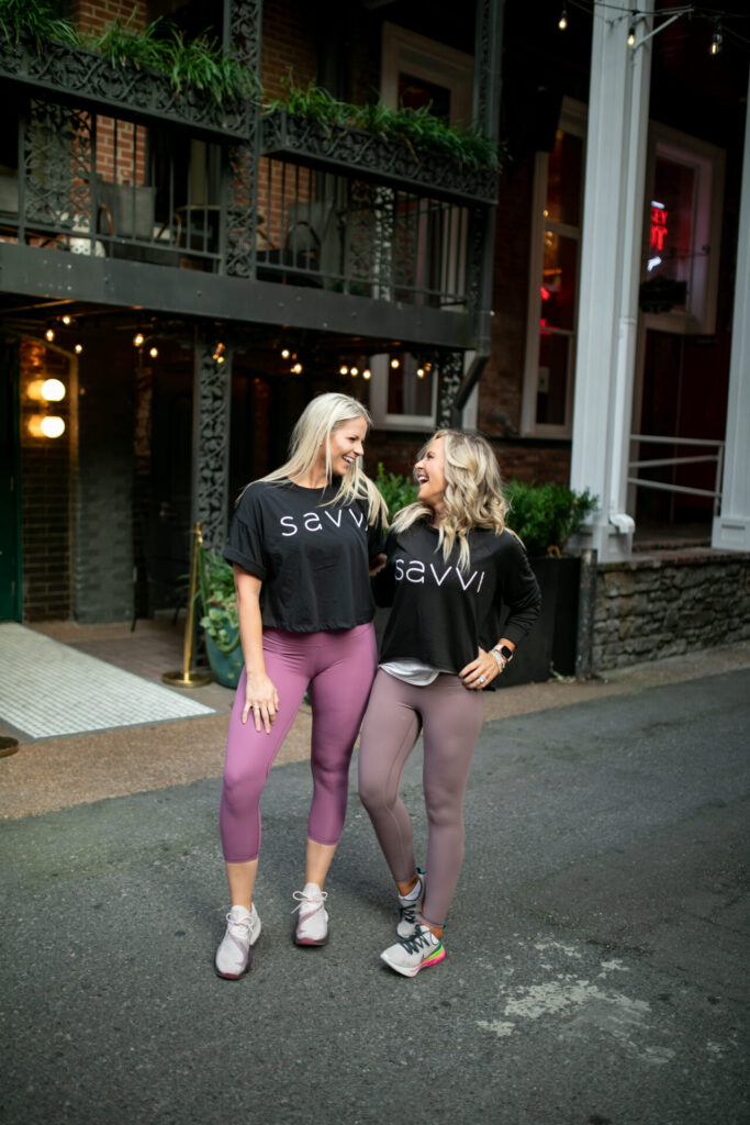 Savvi by popular Nashville fashion blog, Hello Happiness: image of two women standing together outside of a building and wearing Savvi leggings, Savvi t-shirts, and athletic sneakers.  