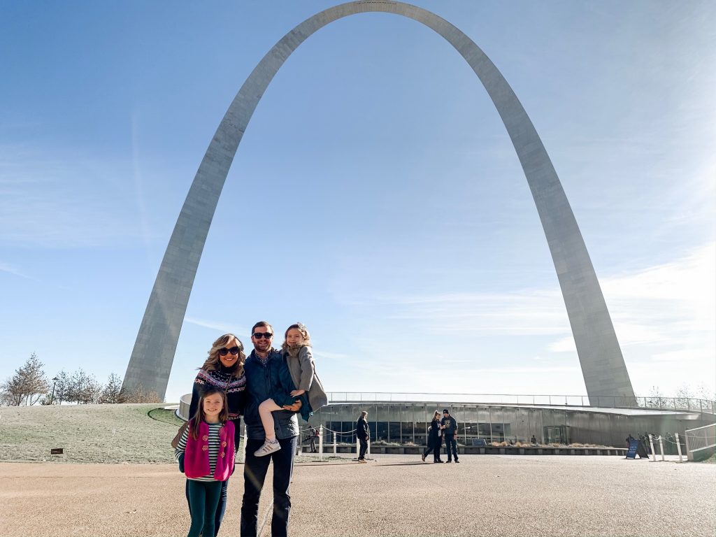 Meet Me for a Weekend in St. Louis | The Perfect Family Getaway by popular travel blog, Hello Happiness: image of family standing in front of the St. Louis Gateway Arch.