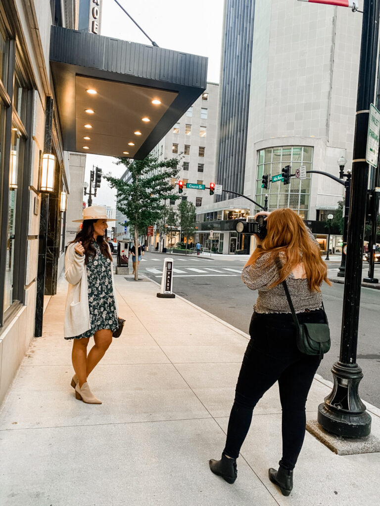 Staycation Ideas by popular Nashville travel blog, Hello Happiness: image of a woman standing in front of a building in Nashville, TN while getting her picture taken by a photographer. 