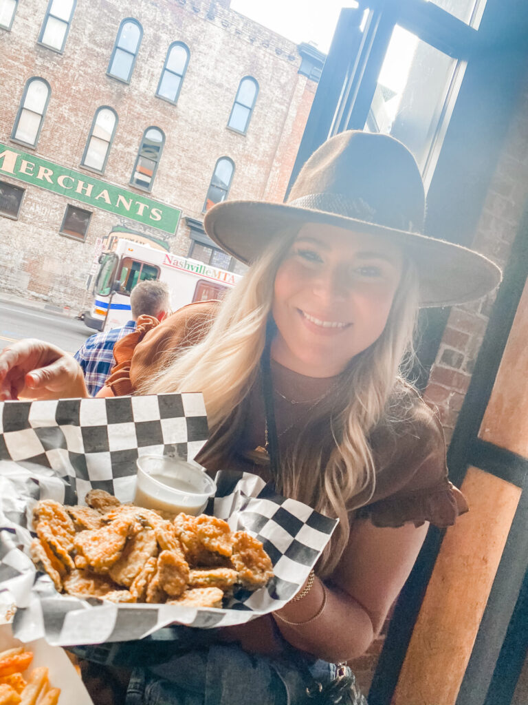 Staycation Ideas by popular Nashville travel blog, Hello Happiness: image of a woman holding up a plate of deep friend pickles. 