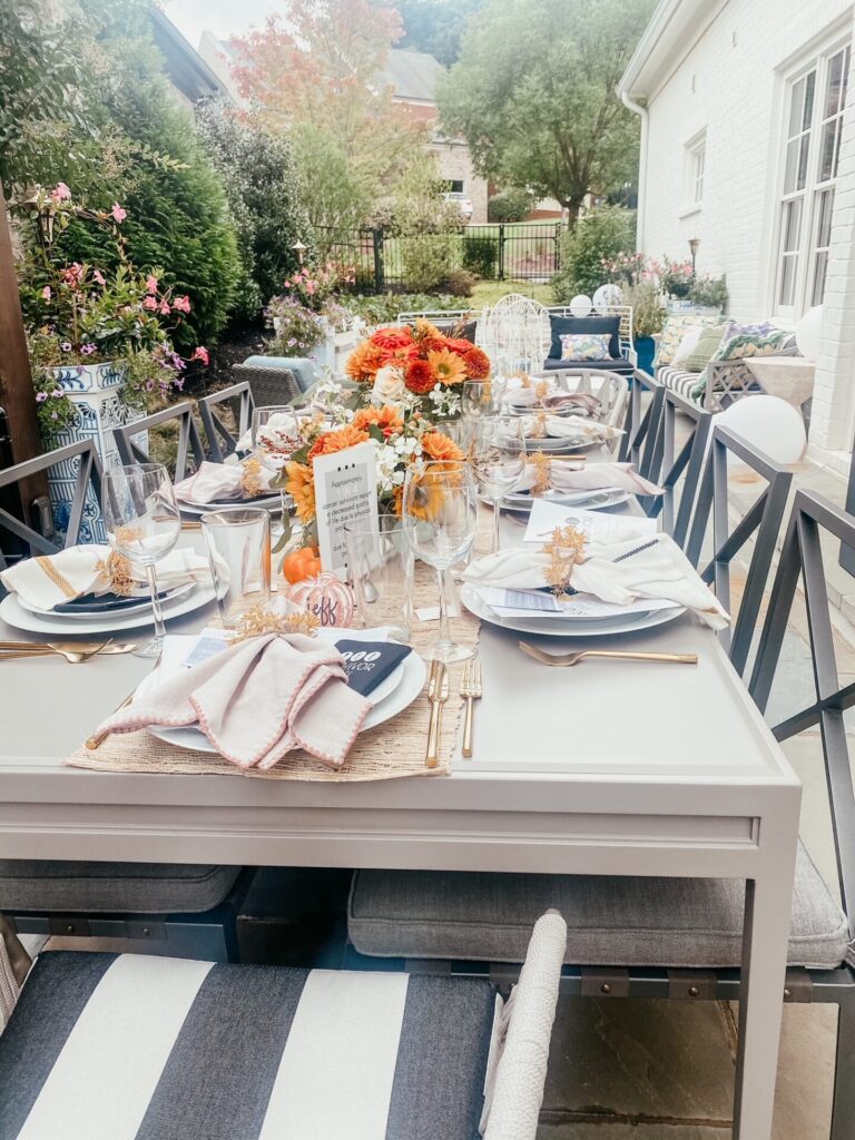 Dinner Party Ideas by popular Nashville lifestyle blog, Hello Happiness: image of a table set with Pottery Barn dishes, Target decorative napkins, Target gold flatware, orange flower arrangements and Hester & Cook pumpkin place cards. 