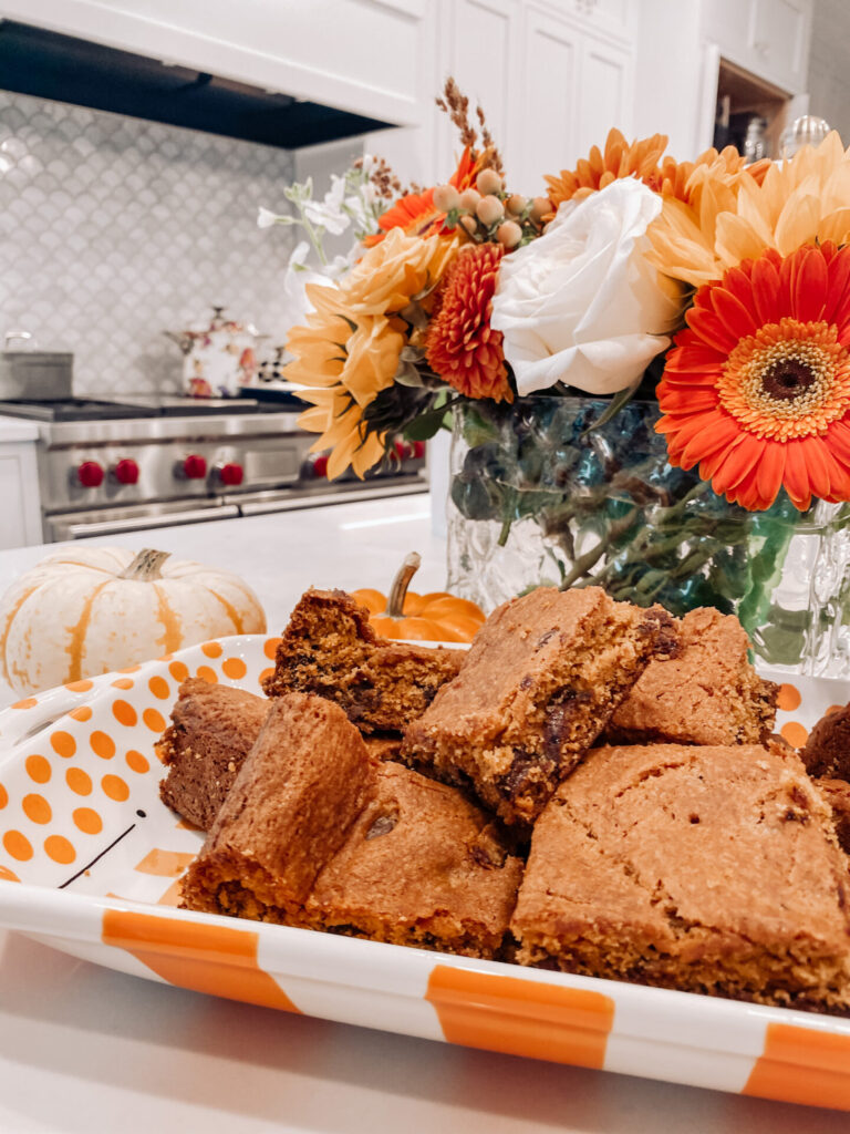 Pumpkin Chocolate Chip by popular Nashville food blog, Hello Happiness: image of pumpkin chocolate chip blondies on a orange and white plate. 