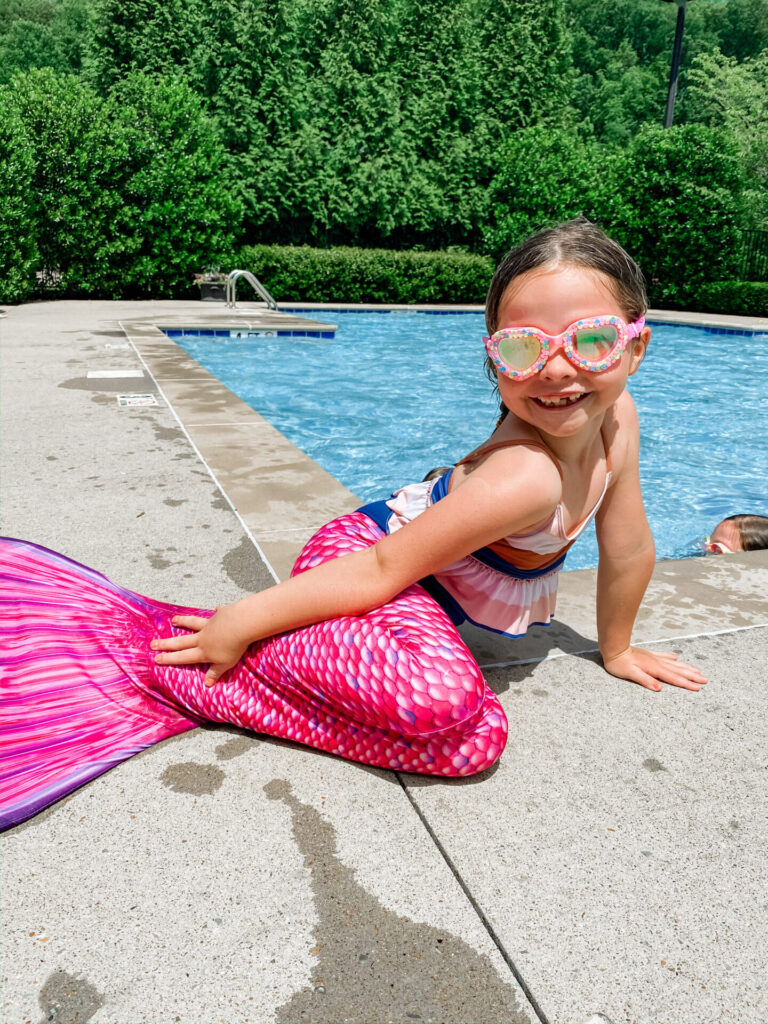 Amazon Favorites by popular Nashville life and style blog, Hello Happiness: image of a little girl sitting by the pool and wearing a pink mermaid tail and bling2o goggles. 