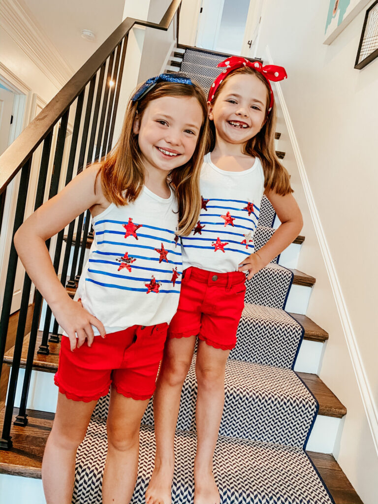 4th of July Fashion by popular Nashville fashion blog, Hello Happiness: image of two girls standing next to each other and wearing a Target Cat & Jack Girls' Eyelet Hem Jean Shorts, Target Cat & Jack Girls' Flip Sequin Stars and Stripes Tank Top, and Amazon Lethez Hairband.