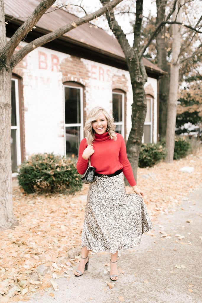 Cheers to Chicos RED by popular Nashville fashion blog, Hello Happiness: image of a woman outside wearing a Chicos red CASHMERE TURTLENECK, Chicos LEOPARD-PRINT MAXI SKIRT, Chicos SIMULATED STONE RING, and carrying a Chicos CONVERTIBLE TWEED SHOULDER BAG.