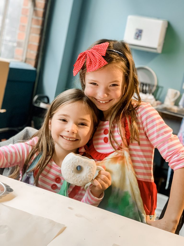 All Our Favorite Family Holiday Traditions by popular life and style blog, Hello Happiness: image of two girls standing together in a pottery shop. 