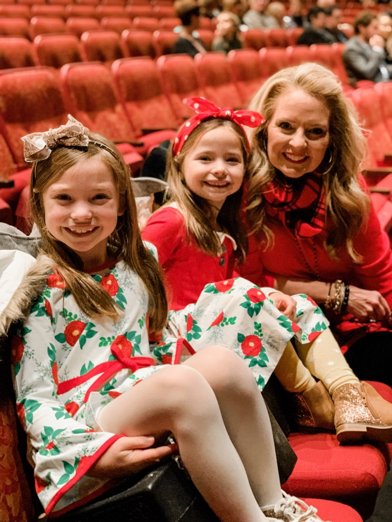 All Our Favorite Family Holiday Traditions by popular life and style blog, Hello Happiness: image of two girls sitting with their grandma and wearing Eleanor Rose Christmas Rose dresses. 
