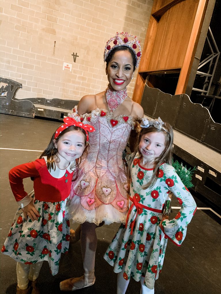 All Our Favorite Family Holiday Traditions by popular life and style blog, Hello Happiness: image of two girls standing with a ballerina and wearing Eleanor Rose Christmas Rose dresses. 