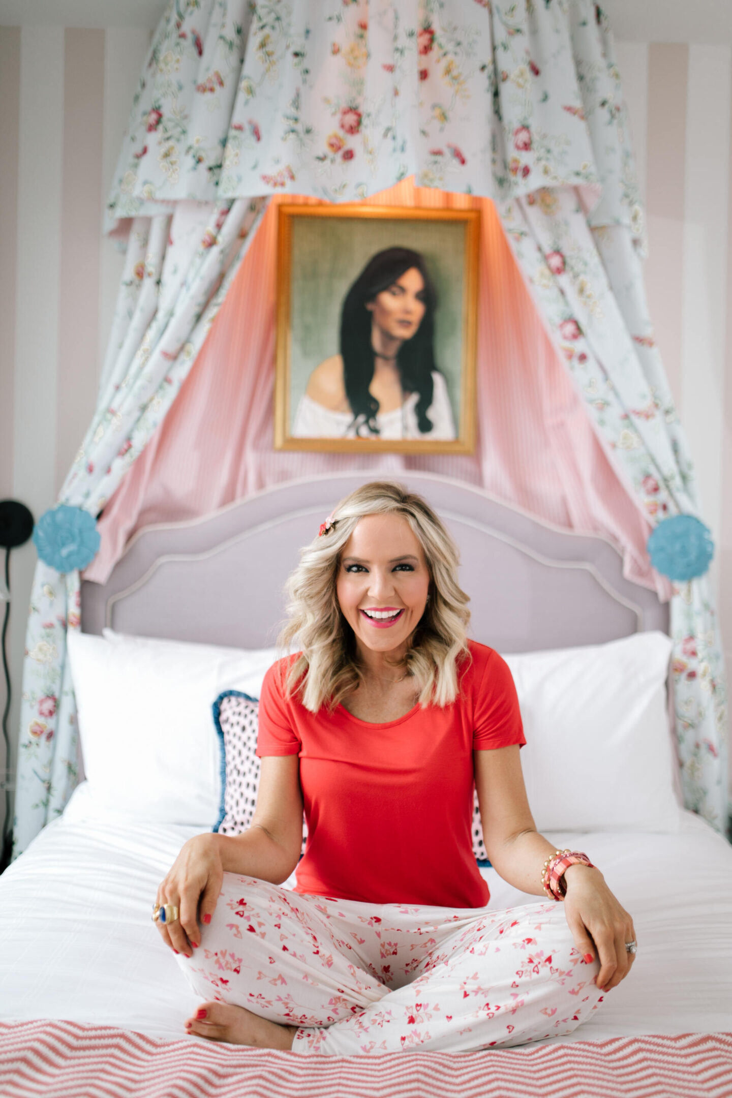 Nashville Hot Spots by popular Nashville travel blog, Hello Happiness: image of Natasha Stoneking wearing a red t-shirt and red and white floral print pants while sitting on a bed. 