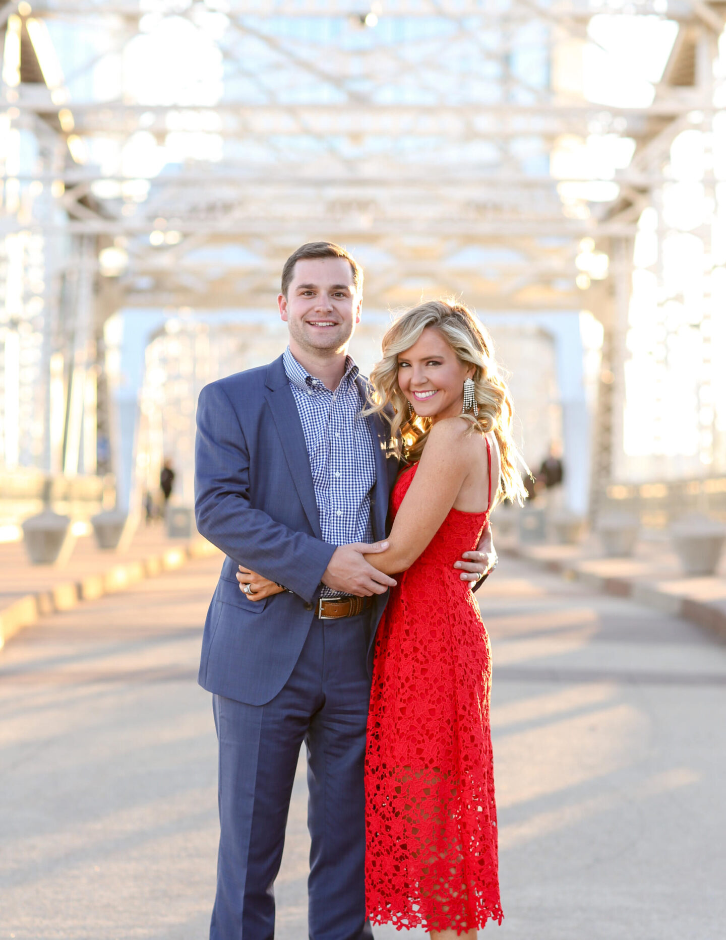 10 Year Wedding Anniversary by popular Nashville lifestyle blog, Hello Happiness: image of a husband and wife standing together and wearing a blue suite and red lace dress while standing on a bridge. 