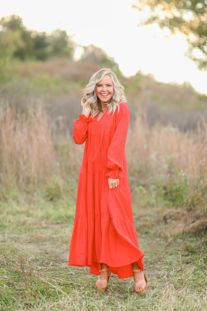Holiday Gift Ideas by popular Nashville life and style blog, Hello Happiness: image of Natasha Stoneking wearing a red tiered maxi dress and standing in a field. 